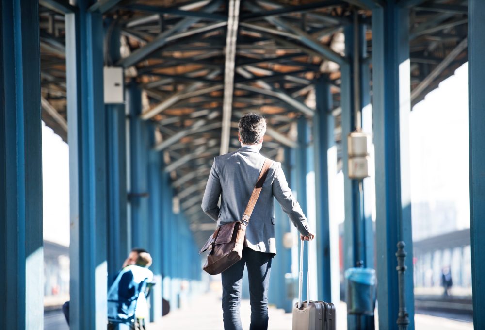Handsome mature businessman in a city. Man walking on the railway platform on the train station. Rear view.