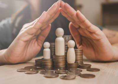 Family insurance plan protect. Help medicine protection. Father mother children insurance. A hand is protecting three small figurines and a pile of coins. Concept of financial security and protection.